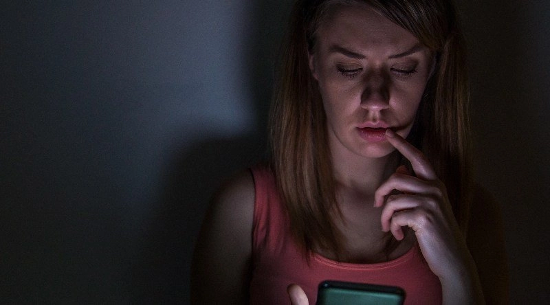 Mujer mira el móvil en la oscuridad